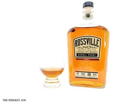 White background tasting shot with the Rossville Union Barrel Proof Rye bottle and a glass of whiskey next to it.
