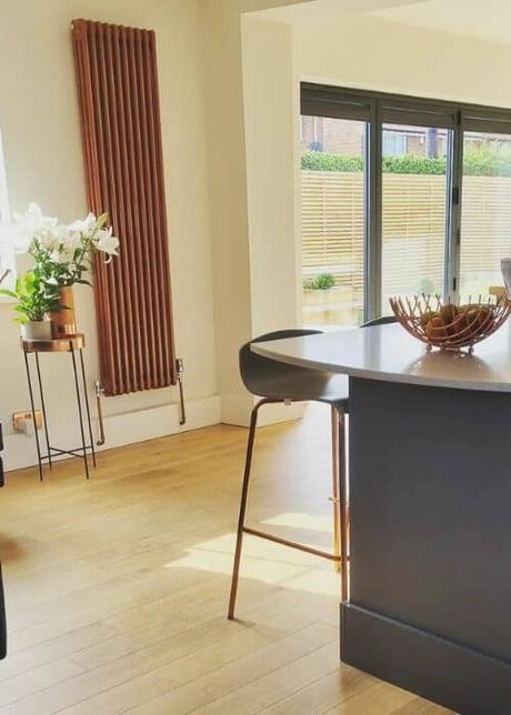 vertical copper column radiator in a white kitchen