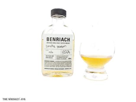 White background tasting shot with the Benriach Smoke Season 2nd Edition sample bottle and a glass of whiskey next to it.