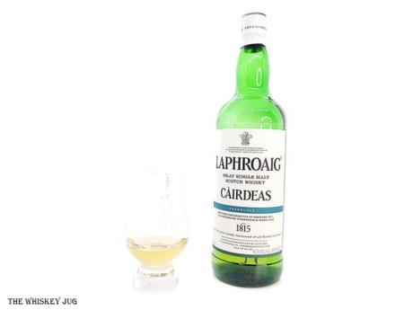 White background tasting shot with the 2022 Laphroaig Cairdeas Warehouse 1 bottle and a glass of whiskey next to it.