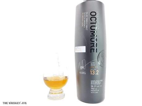 White background tasting shot with the Octomore 13.2 bottle and a glass of whiskey next to it.