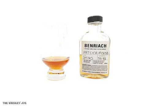 White background tasting shot with the Benriach 24 Years - 1997 Cask 15058 sample bottle and a glass of whiskey next to it.