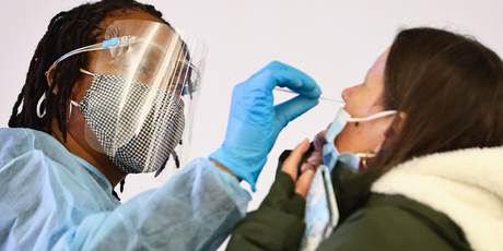 A medical technician performs a nasal swab test on a patient.