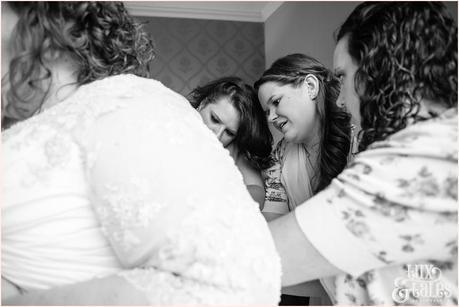 Bridesmaids help bride into dress at Grays court in Yrok