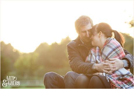 couple wrapped in tartan rug at elvaston castle engagement photo session in autumn 