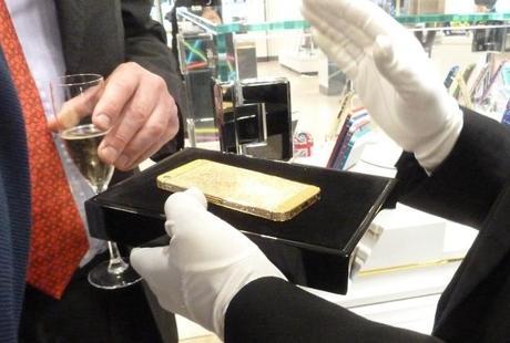 Harrods assistant displays diamond, ruby and sapphire-encrusted gold iPhone in black velvet case to a rich guy holding flute of champagne