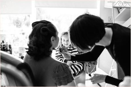 Flower girl watches as bride has makeup applied by Vicky Farr