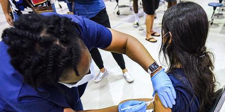 A nurse gives a girl a dose of the Pfizer vaccine at a COVID-19 vaccine clinic at a school. 