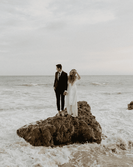 beach wedding newlyweds standing on small rock in the sea