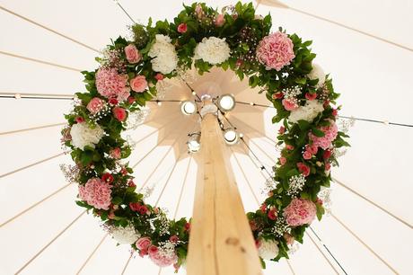 a ring of flowers decorating a wedding marquee