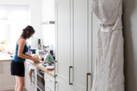 wedding dress hanging in the kitchen with the bride in the background