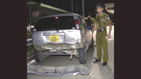 A police officer at the Dodangoda Interchange inspecting one of the damaged vehicles. 