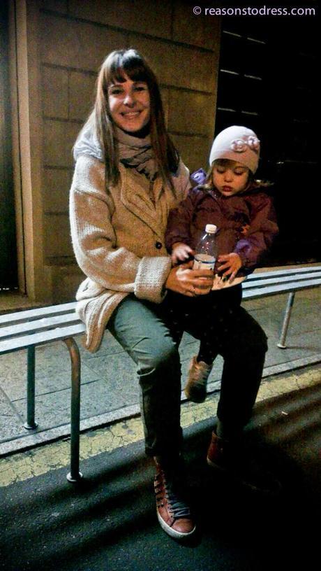 Italian Mom Street Style – The Coatigan Spotted A mom with her daughter on her lap wearing a cream beige coatigan and green pants in front of an ice cream shop parlour gelateria in Modena Italy reasonstodress.com