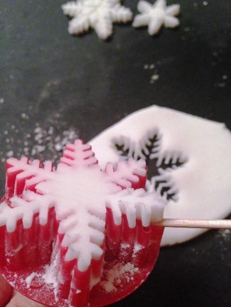 extracting white snowflake fondant shape from intricate cutter using cocktail stick delicate work