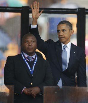 President Obama waves standing next to the sign language interpreter after making his speech at the memorial service for former South African president Nelson Mandela at the FNB Stadium in Soweto near Johannesburg, Tuesday South Africa's deaf federation said on Wednesday that the interpreter on stage for Mandela memorial was a 'fake.'