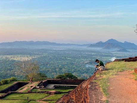 man-sat-looking-at-phone-on-top-of-sigiriya-lions-rock