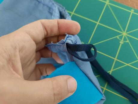 Threading two blue shoelaces as the bag's closing