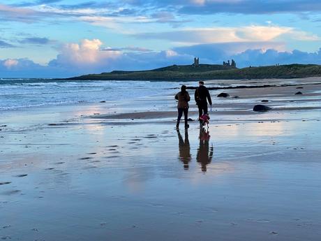 couple-walking-together-on-dunstanburgh-beach-in-northumberland