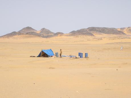 man-standing-by-blue-tent-in-the-desert-in-sudan