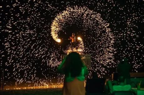 A performer gives a fire performance as the tourists enjoy the act