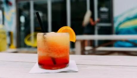 A glass orange juice served on a table with a straw