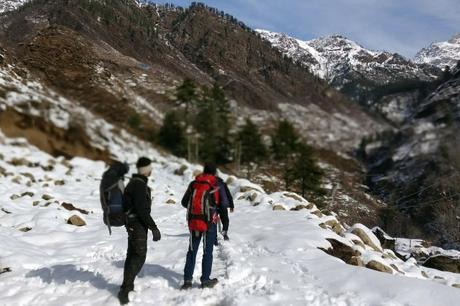 two men walking in the snow in the mountains