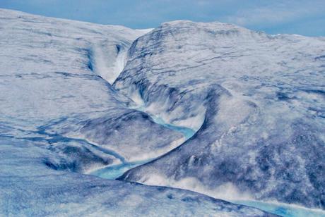 At midnight in July, meltwater flows in a winding channel over the Greenland ice sheet.  Paul Bierman