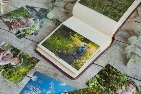 Digital vs traditional photo albums - photo of an album open on a table with photographs scattered around it.