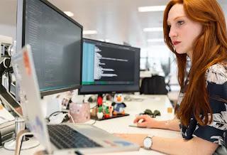 A woman in an office researching proposal management on her computer