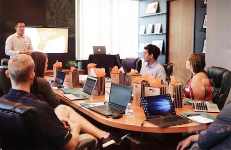 A team in an office discussing proposal management during a meeting