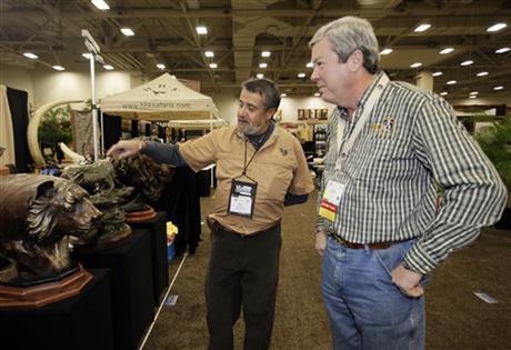 Dallas Safari Club executive director Ben Carter, right, talks with wildlife artist Raj S. Paul at his exhibit booth in the Dallas Convention Center as preparations continue for the clubs weekend show, Wednesday, Jan. 8, 2014, in Dallas. The FBI is investigating death threats made against members of the Dallas Safari Club, which intends to auction off a rare permit to hunt an endangered black rhino, an FBI spokeswoman said Wednesday