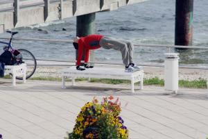 Man in athletic clothing doing reverse table on an outdoor bench.