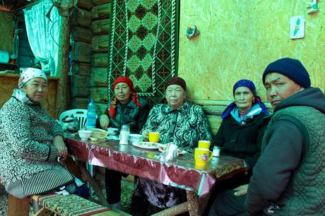 kyrgyz people sitting around a table sharing a meal together