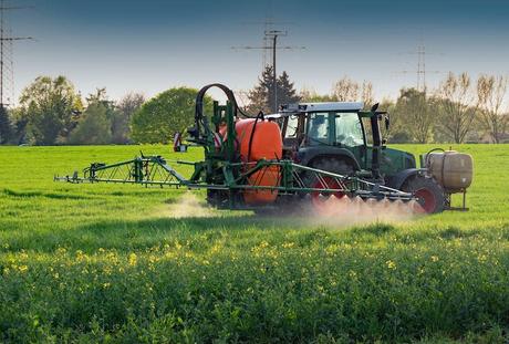 A tractor equipped with a tank that sprays chemicals on a crop.