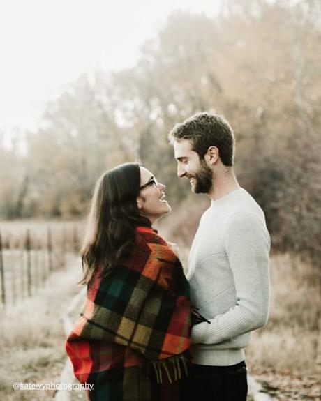 winter engagement photos girl with blanket looking on the guy