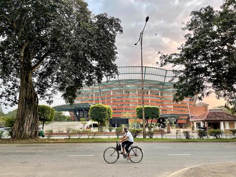 cyclist on the road with the Colombo National Performing Arts Theatre in the background