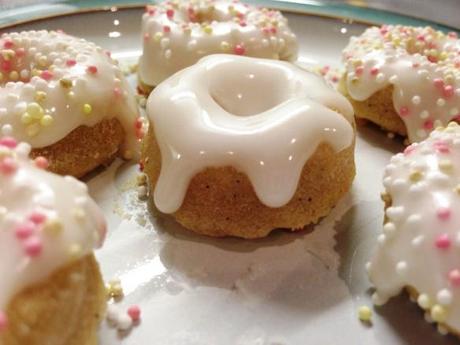 dripping white icing on freshly baked mini doughnuts with sugar sprinkles