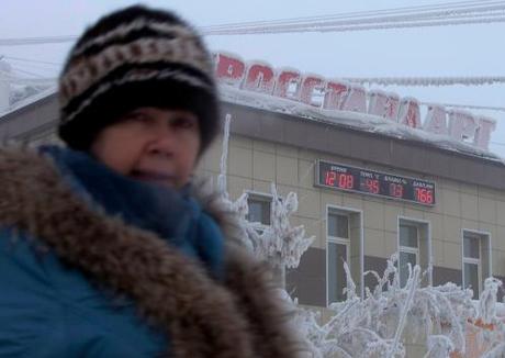 A woman passes a board on a building, displaying the local time, temperature, humidity and air pressure in Yakutsk. (photo: Maxim Shemetov, Reuters)
