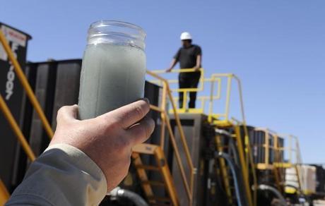 A jar holding waste water from hydraulic fracturing is held up to the light at a recycling site in Midland, Texas, Sept. 24, 2013. With fresh water not as plentiful companies have been looking for ways to recycle their waste. CREDIT: AP Photo/Pat Sullivan