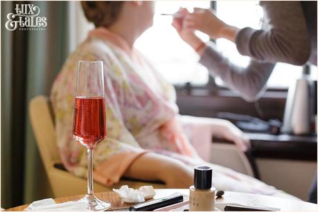 Cedar Court Grand Wedding bride gets makeup applied inw indow with pink champaign