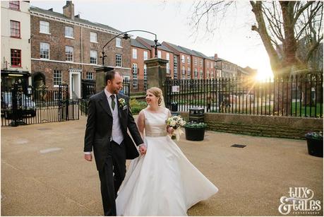 Bride and groom walk in York with the low winter light behind them. they are relaxed and smiling