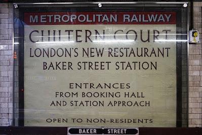 Photograph of an advertisement, now behind glass, reading 'Metropolitan Line. Chiltern Court - London's New Restaurant - Baker Street Station. Entrances from Booking Hall and Station Approach. Open to non-residents.'