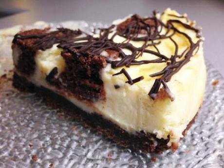 white chocolate and brownie cheesecake sliced topped with dark chocolate swirls crunchy biscuit base