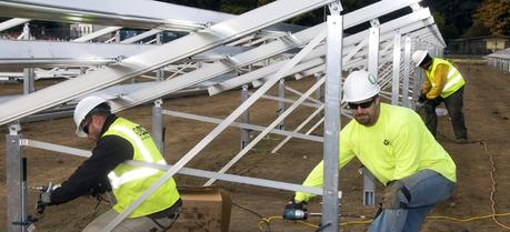 Workers secure the base of a solar panel frame