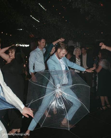 documentary style wedding photography groom dancing with an umbrella