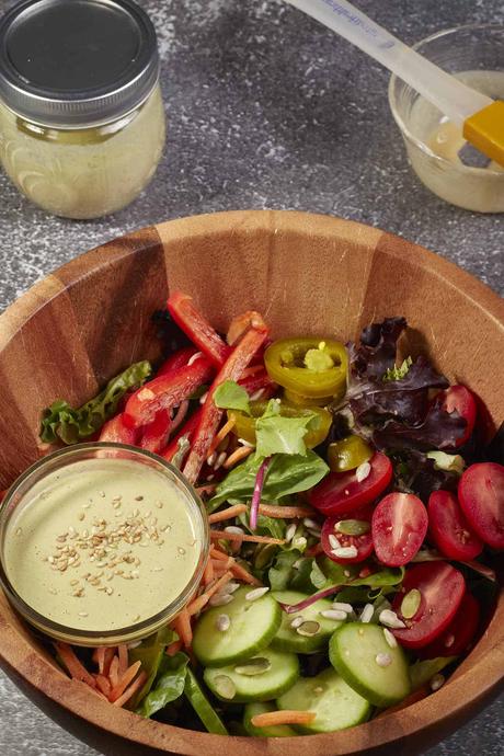 salad with a jar of vegan tahini salad dressing on the side