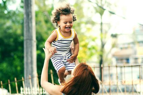 7 best handbags for busy moms - woman raising laughing child in her arms