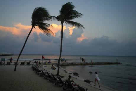 People lounge on the beach as the sun sets ahead of Hurricane Beryl's expected arrival, in...