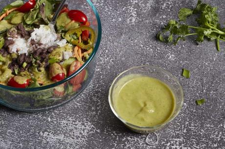 a big salad with a little dish of green chile lime salad dressing