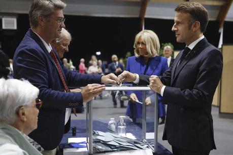 Projections show voters rejecting the far right : NPR French President Emmanuel Macron, right, votes for the second round of the legislative elections in Le Touquet-Paris-Plage, northern France, on Sunday.